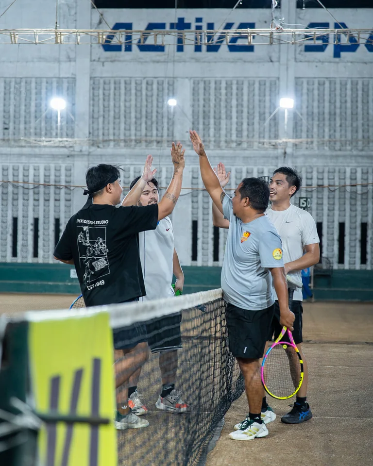 Players high-fiving across the net after a doubles match
